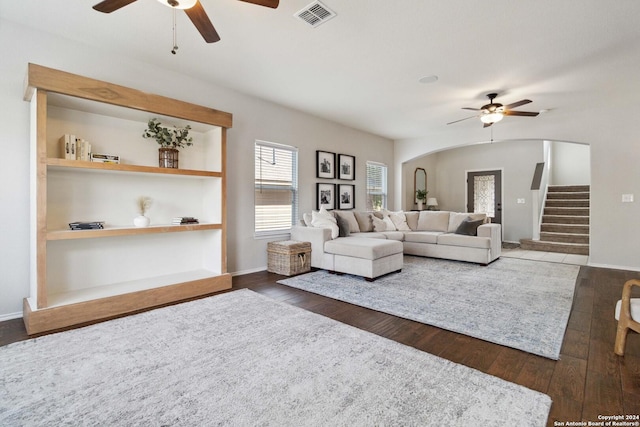 living area with visible vents, arched walkways, a ceiling fan, dark wood-style floors, and stairway