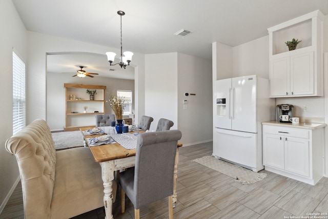 dining space featuring ceiling fan with notable chandelier