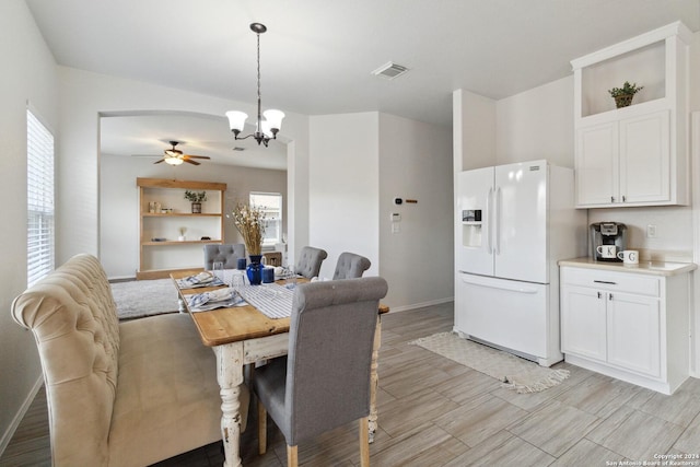 dining space featuring light wood finished floors, baseboards, visible vents, arched walkways, and ceiling fan with notable chandelier