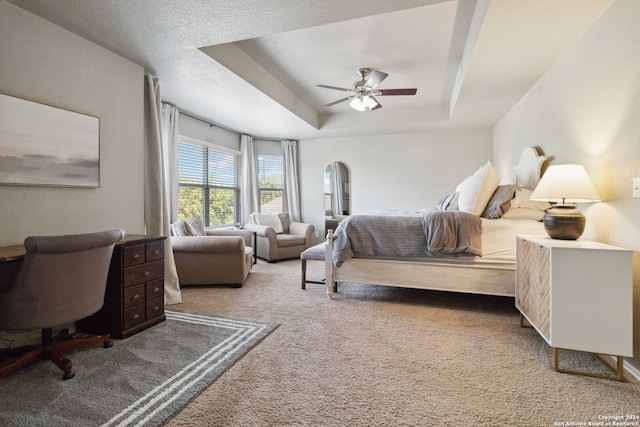 carpeted bedroom featuring a raised ceiling, a textured ceiling, and ceiling fan