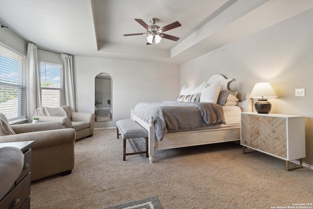 carpeted bedroom featuring a raised ceiling and ceiling fan