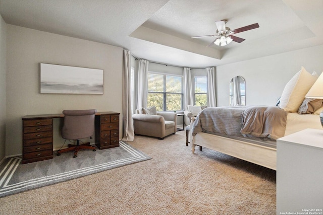 bedroom with ceiling fan, a raised ceiling, and carpet flooring