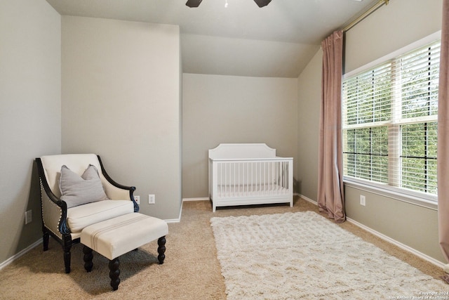 bedroom with vaulted ceiling, a nursery area, ceiling fan, and carpet flooring