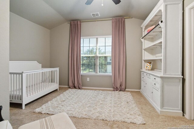 carpeted bedroom with ceiling fan and a crib