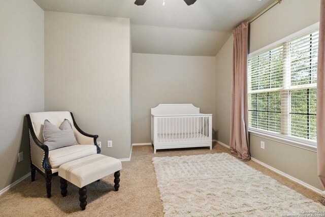 bedroom with a nursery area, light carpet, and ceiling fan