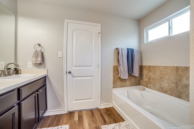 bathroom with vanity, a bath, and wood-type flooring