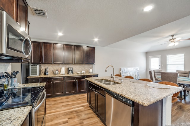 kitchen with backsplash, light hardwood / wood-style flooring, appliances with stainless steel finishes, sink, and ceiling fan