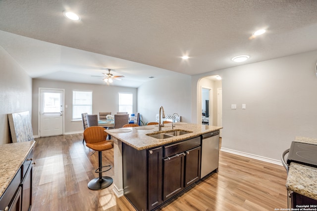 kitchen featuring dishwasher, light wood-type flooring, plenty of natural light, sink, and an island with sink