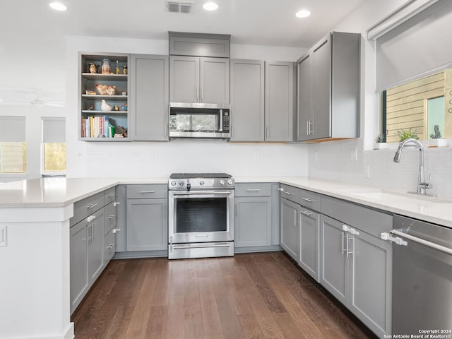 kitchen featuring appliances with stainless steel finishes, sink, dark wood-type flooring, and decorative backsplash