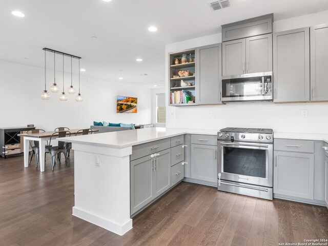 kitchen featuring appliances with stainless steel finishes, dark hardwood / wood-style flooring, kitchen peninsula, and decorative backsplash