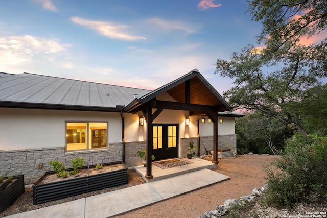 back house at dusk with a patio and french doors