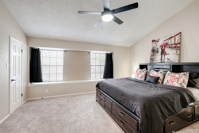 bedroom featuring ceiling fan, vaulted ceiling, light carpet, and a textured ceiling