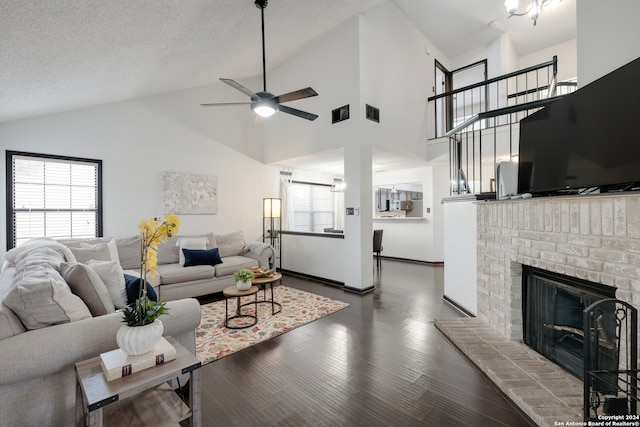 living room with a fireplace, ceiling fan, dark hardwood / wood-style floors, high vaulted ceiling, and a textured ceiling