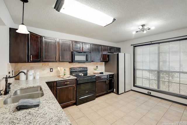 kitchen with black appliances, pendant lighting, light stone countertops, and sink