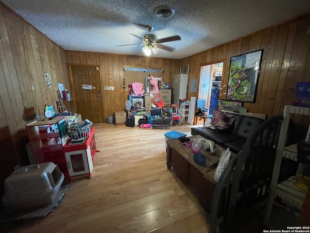 miscellaneous room featuring a textured ceiling, hardwood / wood-style floors, wood walls, and ceiling fan