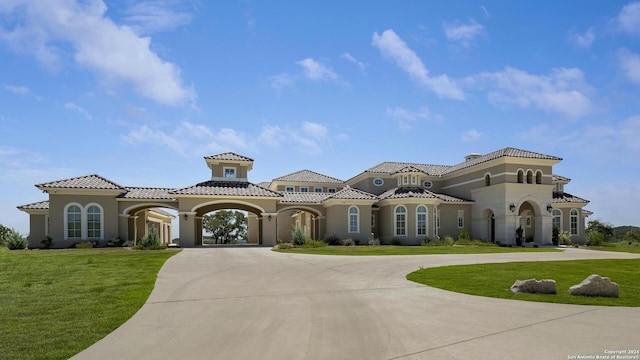 view of front of house featuring a front yard, a tile roof, curved driveway, and stucco siding