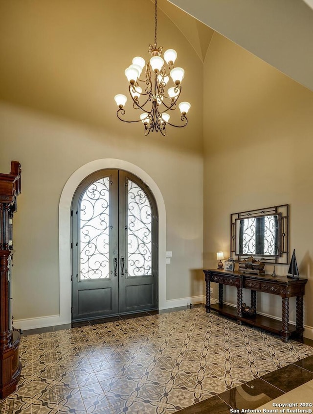 tiled entrance foyer with arched walkways, french doors, an inviting chandelier, high vaulted ceiling, and baseboards