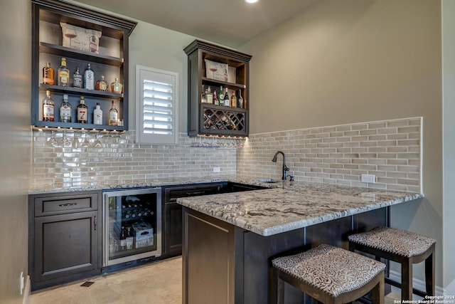 bar featuring tasteful backsplash, beverage cooler, indoor wet bar, and a sink