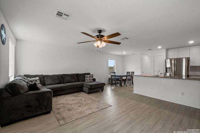 living room with ceiling fan and light hardwood / wood-style floors