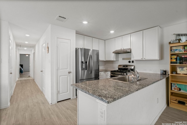 kitchen featuring light wood-type flooring, dark stone counters, white cabinetry, kitchen peninsula, and appliances with stainless steel finishes