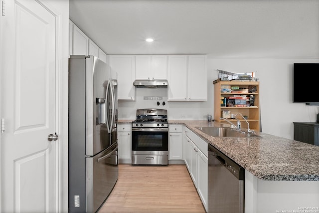 kitchen featuring stainless steel appliances, light hardwood / wood-style floors, white cabinetry, sink, and dark stone counters