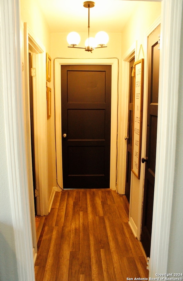 hall with dark wood-type flooring and a chandelier