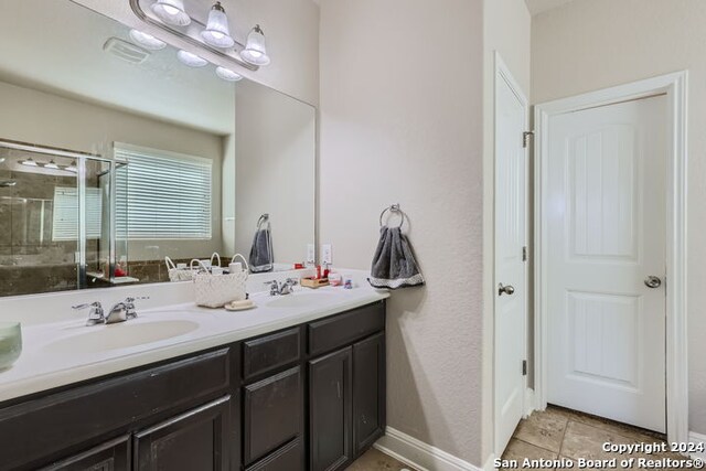 bathroom with tile patterned floors, walk in shower, and vanity