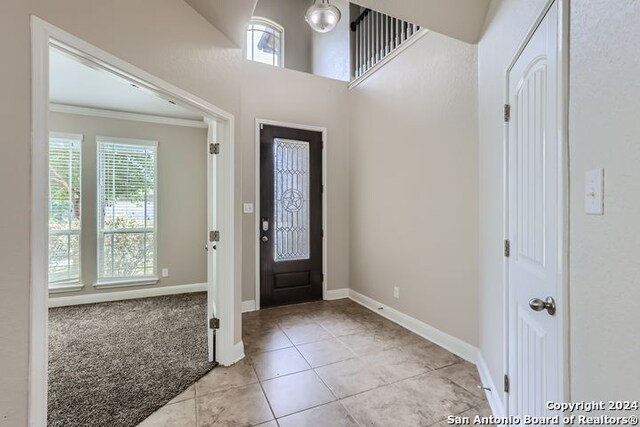 foyer entrance with crown molding and light tile patterned floors