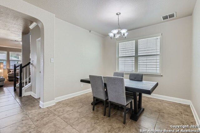 tiled dining area featuring a notable chandelier and a textured ceiling