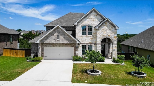 french country home featuring a garage, driveway, a front lawn, and fence