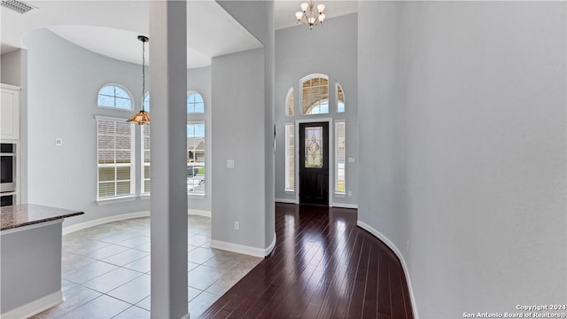 entrance foyer with hardwood / wood-style flooring, a chandelier, and a towering ceiling