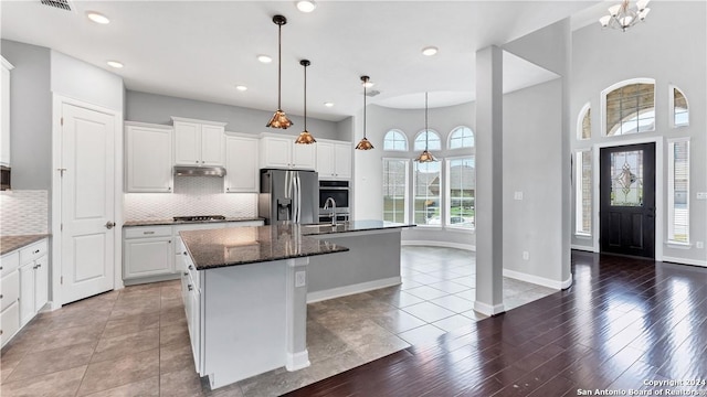 kitchen featuring backsplash, stainless steel appliances, a kitchen island with sink, and tile patterned floors