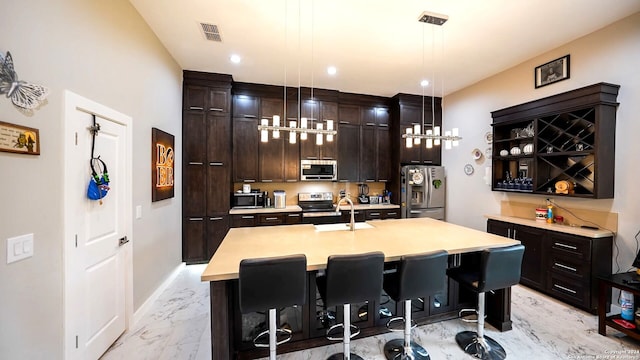 bar with appliances with stainless steel finishes, decorative light fixtures, sink, and dark brown cabinetry