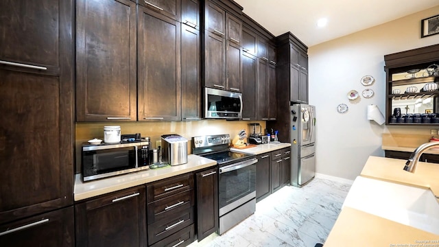 kitchen with stainless steel appliances, sink, light tile patterned floors, and dark brown cabinets