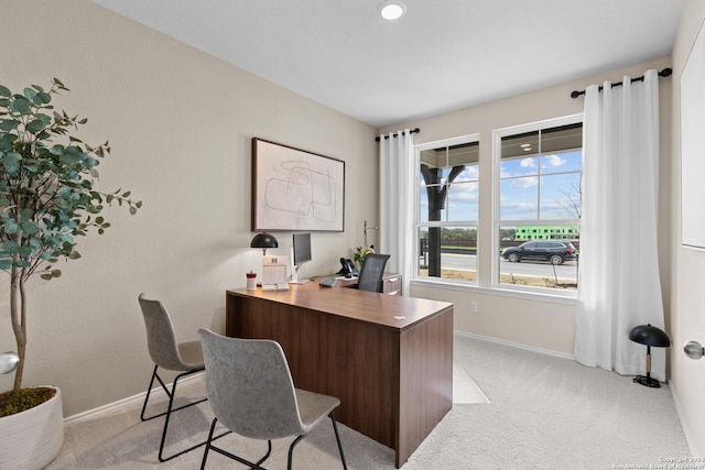 office area featuring light carpet and baseboards