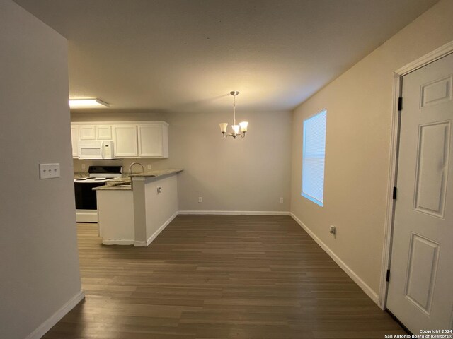 kitchen with dark hardwood / wood-style floors, an inviting chandelier, white appliances, kitchen peninsula, and white cabinetry