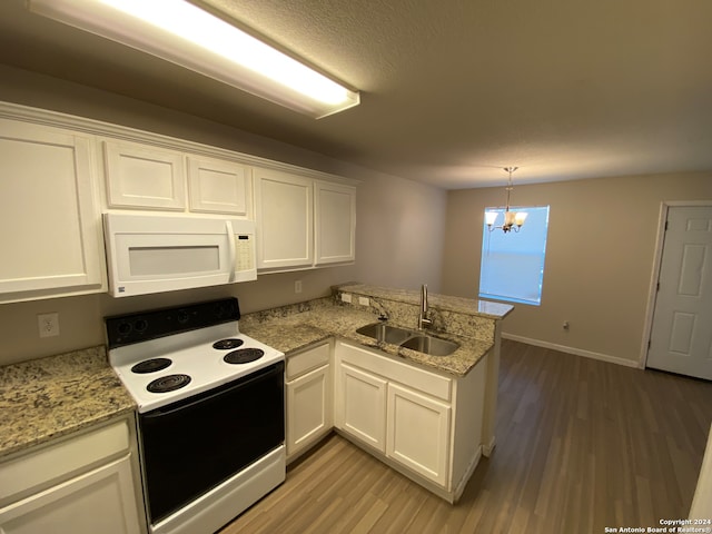 kitchen with hardwood / wood-style floors, white appliances, kitchen peninsula, an inviting chandelier, and sink