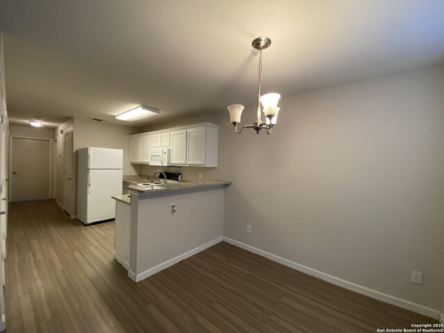 kitchen with white appliances, a notable chandelier, hardwood / wood-style floors, kitchen peninsula, and white cabinetry