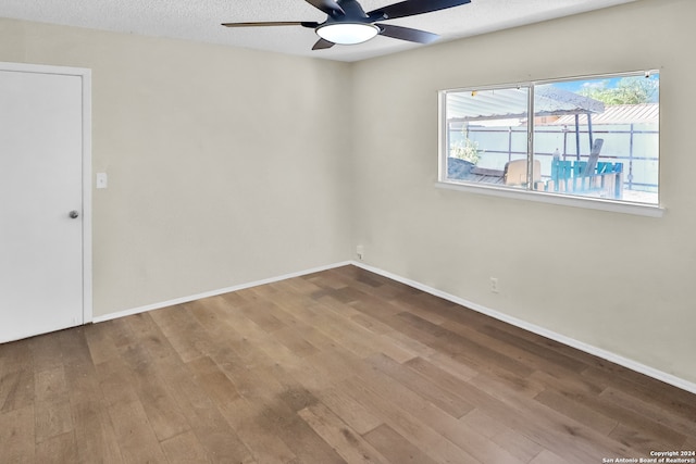 spare room with a textured ceiling, wood-type flooring, and ceiling fan