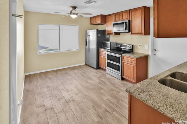 kitchen featuring light hardwood / wood-style flooring, stainless steel appliances, light stone countertops, and ceiling fan