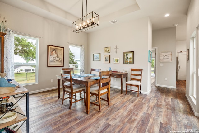 dining area featuring dark wood-type flooring, plenty of natural light, an inviting chandelier, and a towering ceiling