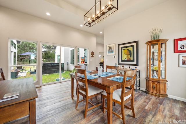 dining room with wood-type flooring, an inviting chandelier, and a high ceiling