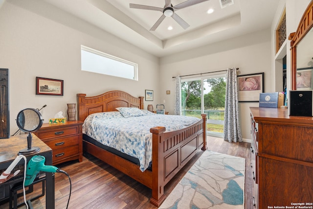 bedroom featuring a tray ceiling, dark hardwood / wood-style flooring, a towering ceiling, and ceiling fan