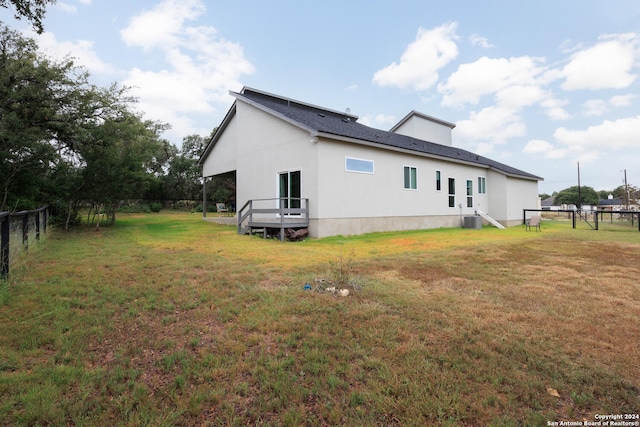 view of side of property with central AC unit and a lawn