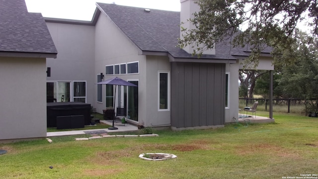 rear view of property featuring a lawn and a hot tub