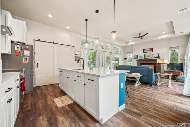 kitchen with plenty of natural light, a barn door, ceiling fan, and a tray ceiling