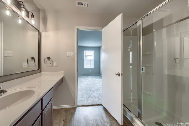 bathroom with vanity, wood-type flooring, and an enclosed shower