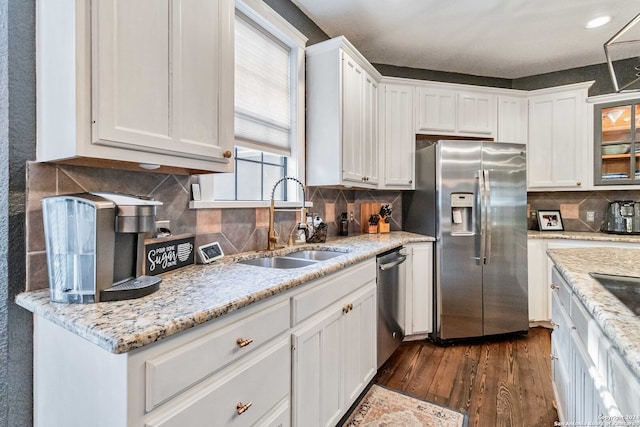 kitchen with dark hardwood / wood-style flooring, backsplash, stainless steel appliances, sink, and white cabinetry