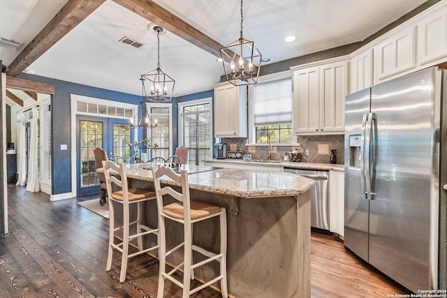 kitchen featuring a wealth of natural light, appliances with stainless steel finishes, beam ceiling, and light hardwood / wood-style floors