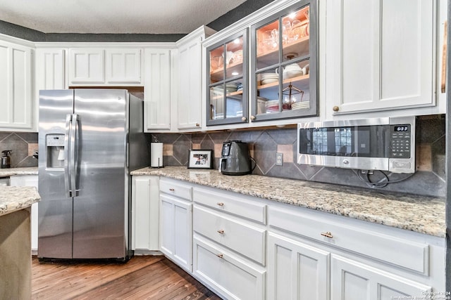 kitchen featuring light hardwood / wood-style floors, stainless steel appliances, white cabinets, and tasteful backsplash